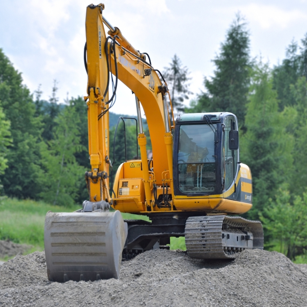 large yellow excavator on a pile of gravel